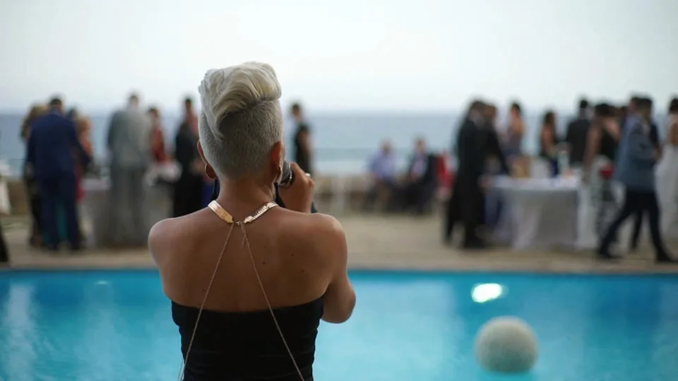 Chloe Ly de espaldas cantando junto a una piscina frente al mar durante el cóctel de una boda